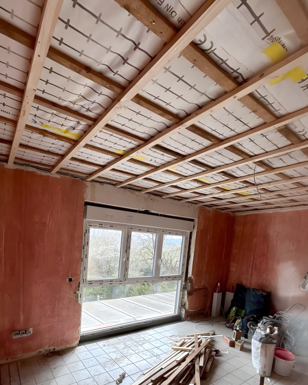 Vorher: Wohnraum im Rohbau mit offener Dachkonstruktion, Ziegelwänden und Baumaterial